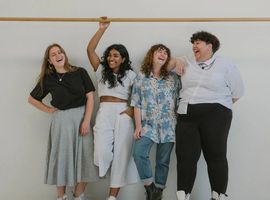 a group of friends standing in front of a white wall all laughing and looking at each other