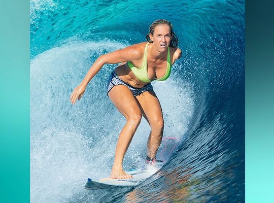 Bethany surfing on a blue wave
