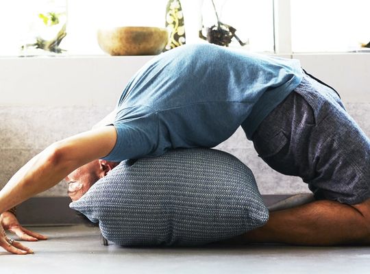 person stretching in backbend with pillow, clinical protection