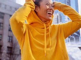 Mujer feliz con buzo con capucha amarilla, la ciencia para saber qué es el sudor