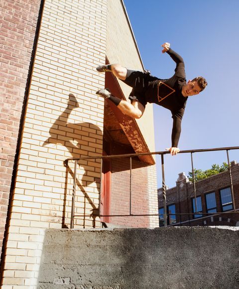  Homme sautant par-dessus une balustrade pendant un mouvement de parkour    