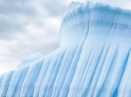 die Seite eines riesigen Eisbergs in strahlend blauem Wasser