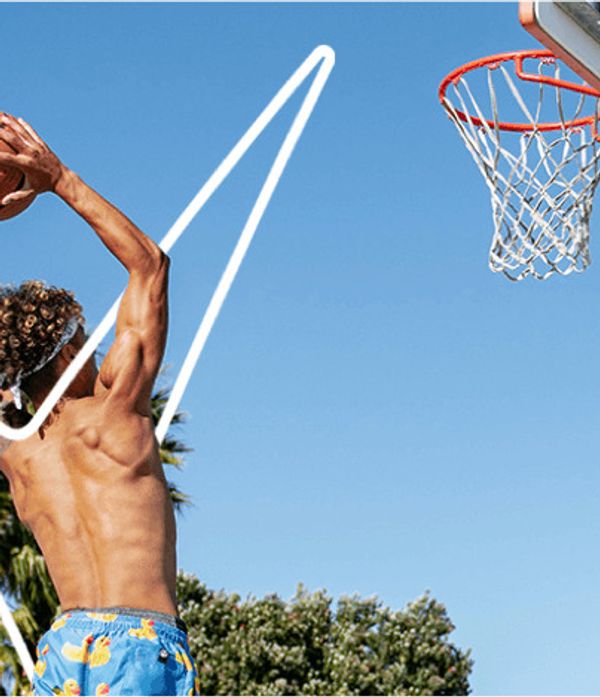Un joueur de basket-ball en short bleu et torse nu saute avec le ballon pour marquer un panier