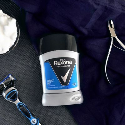 Le Rexona Deo Cobalt Dry Stick est posé sur une serviette bleue. A côté, une lame de rasoir et un coupe-ongles. 