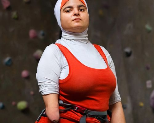 Woman in red in front of climbing wall