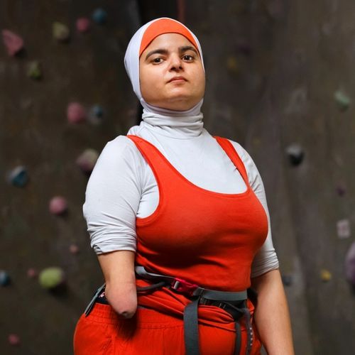 Anouche standing proudly infront of a backdrop of a climbing wall