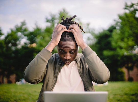 Man working on his laptop pulling at his hair