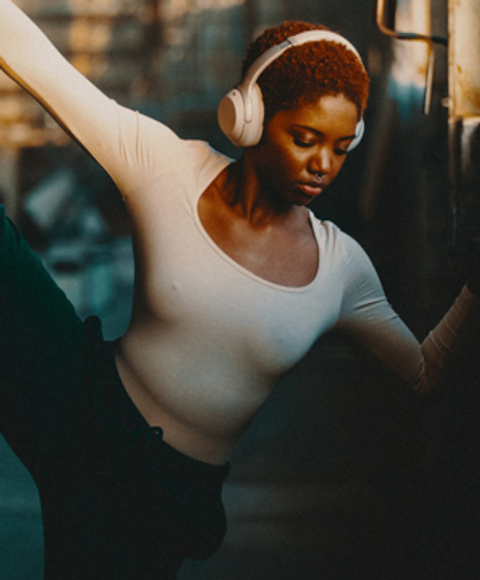 A woman with headphones stretching against the wall