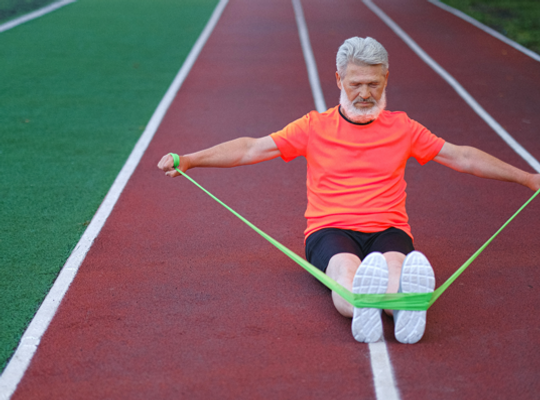 Man stretching with a skipping rope sat on a running track