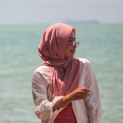 A lady wearing a headscarf standing by the sea