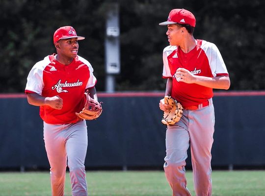Two baseball players in red jersey's running and talking