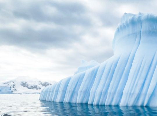 el lado de un iceberg gigante en agua azul brillante