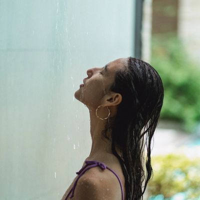 A lady in a shower looking up as water falls over her