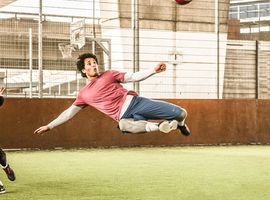 Man playing soccer volleys the ball mid air. 