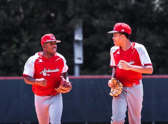 Dos jugadores de beisbol en uniforme rojo corriendo y hablando
