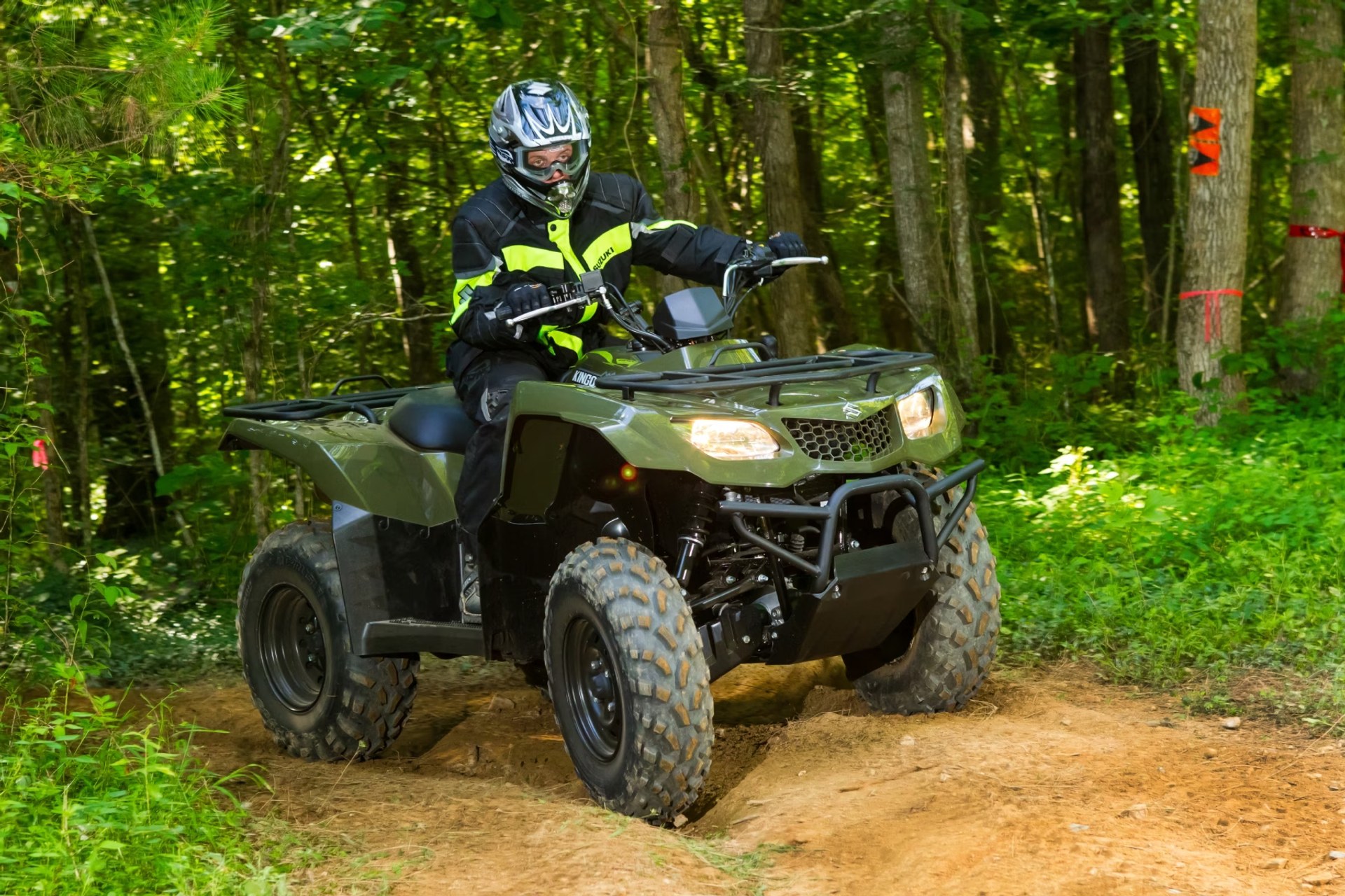 Conductor en Suzuki KingQuad 400 verde recorriendo un sendero off-road en el bosque