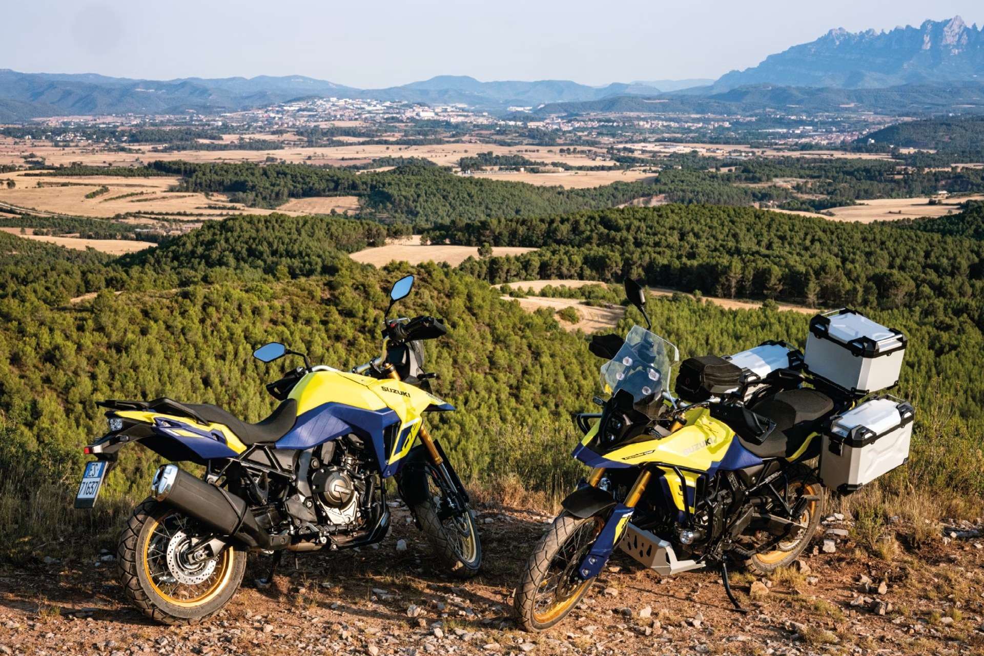 Dos motos Suzuki V-Strom 800DE amarillas estacionadas en un mirador de montaña