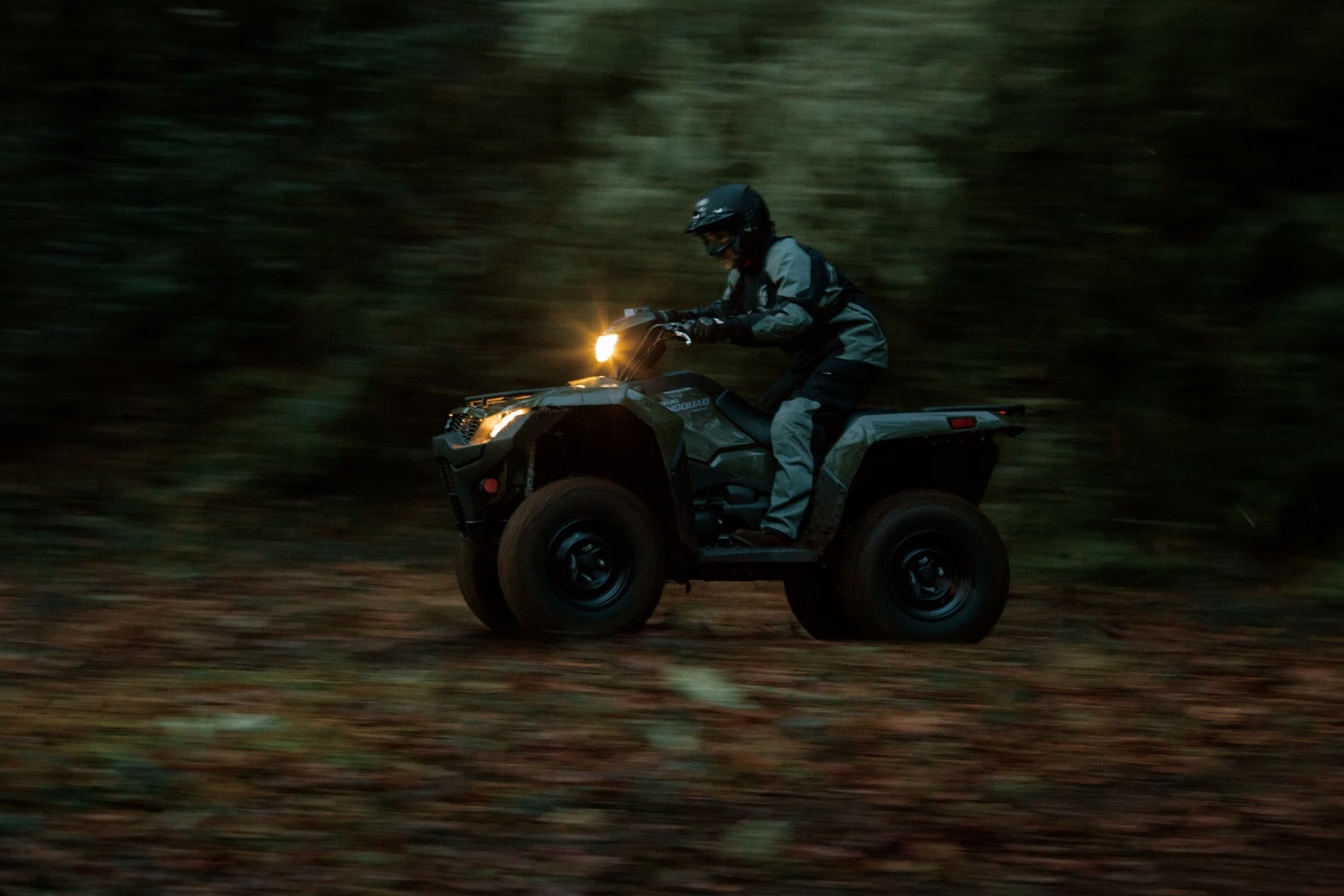 Motociclista conduciendo un Suzuki KingQuad 750 por un sendero de bosque