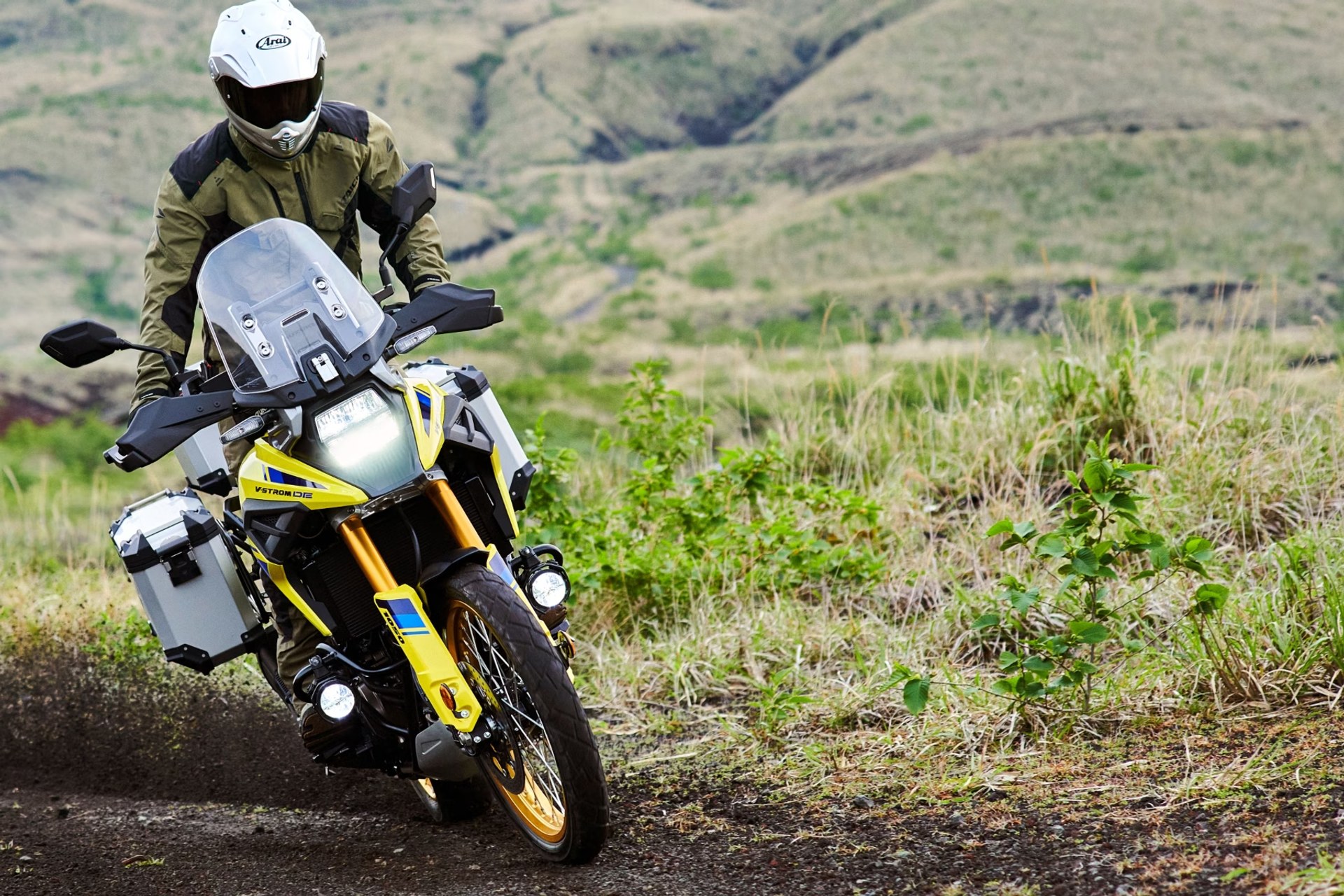 Motociclista en Suzuki V-Strom 1050DE amarilla recorriendo un camino off-road