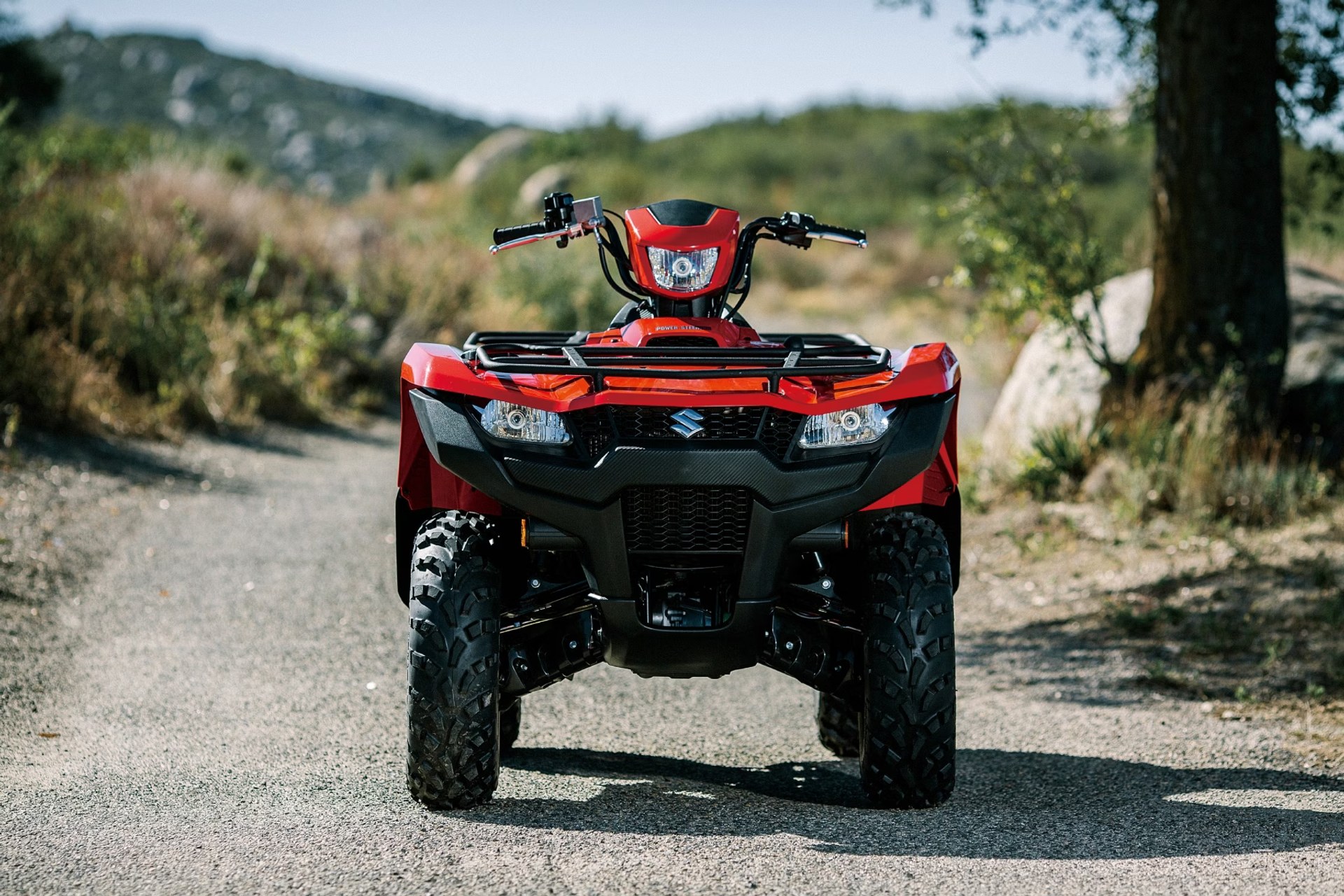 Suzuki KingQuad 750 rojo en vista frontal sobre camino de tierra