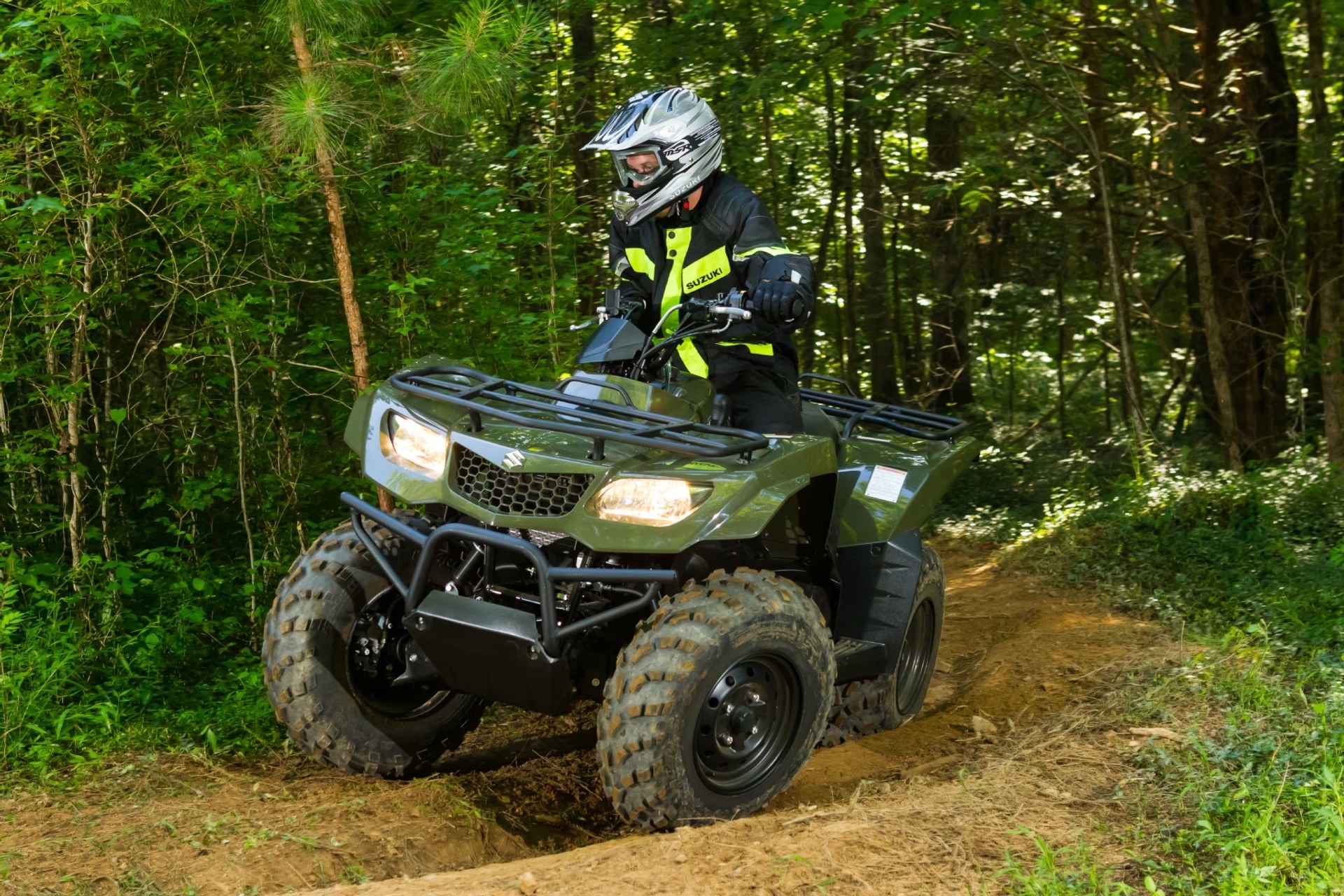 Motociclista conduciendo un Suzuki KingQuad 400 verde por un sendero de bosque