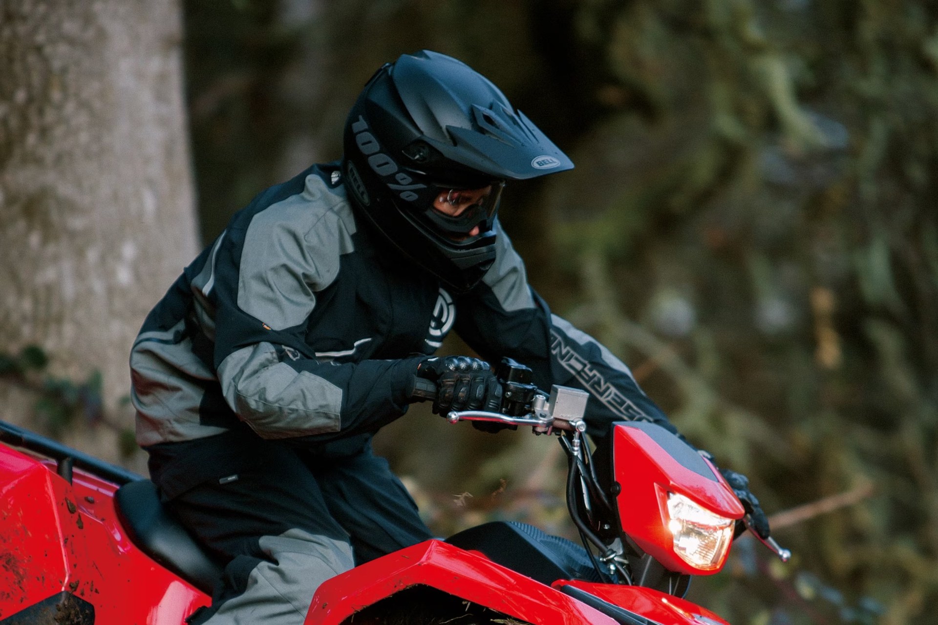 Conductor en Suzuki KingQuad 750 rojo durante una ruta off-road en el bosque