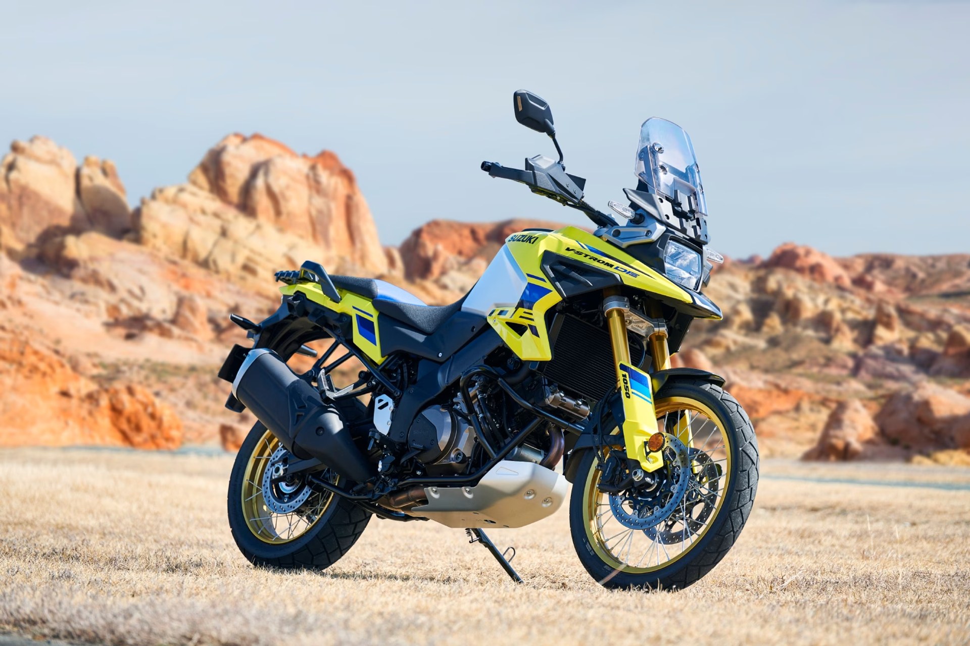 Motocicleta Suzuki V-Strom 1050DE amarilla aparcada en terreno rocoso de montaña