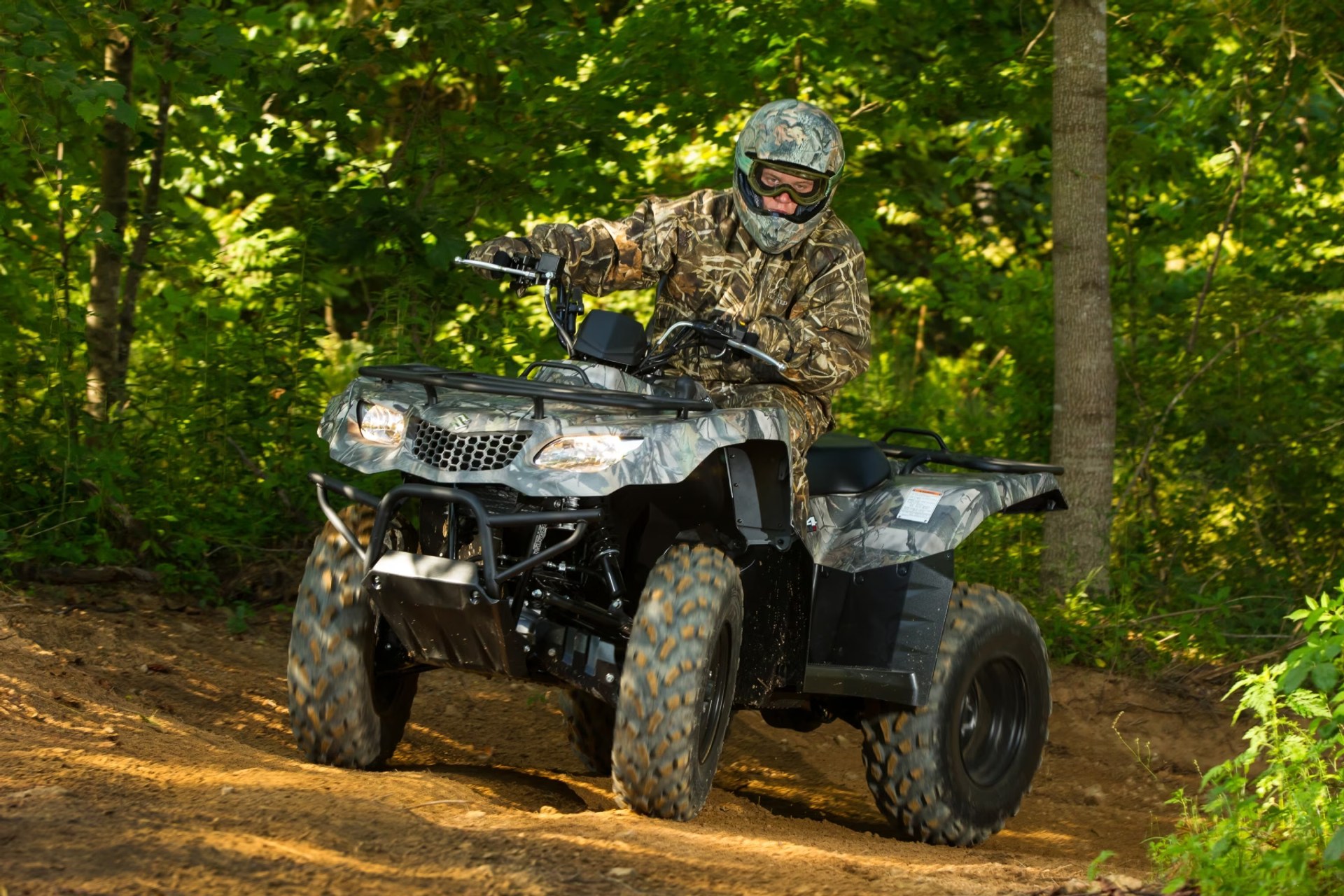 Conductor en Suzuki KingQuad 400 camuflado recorriendo un sendero de bosque