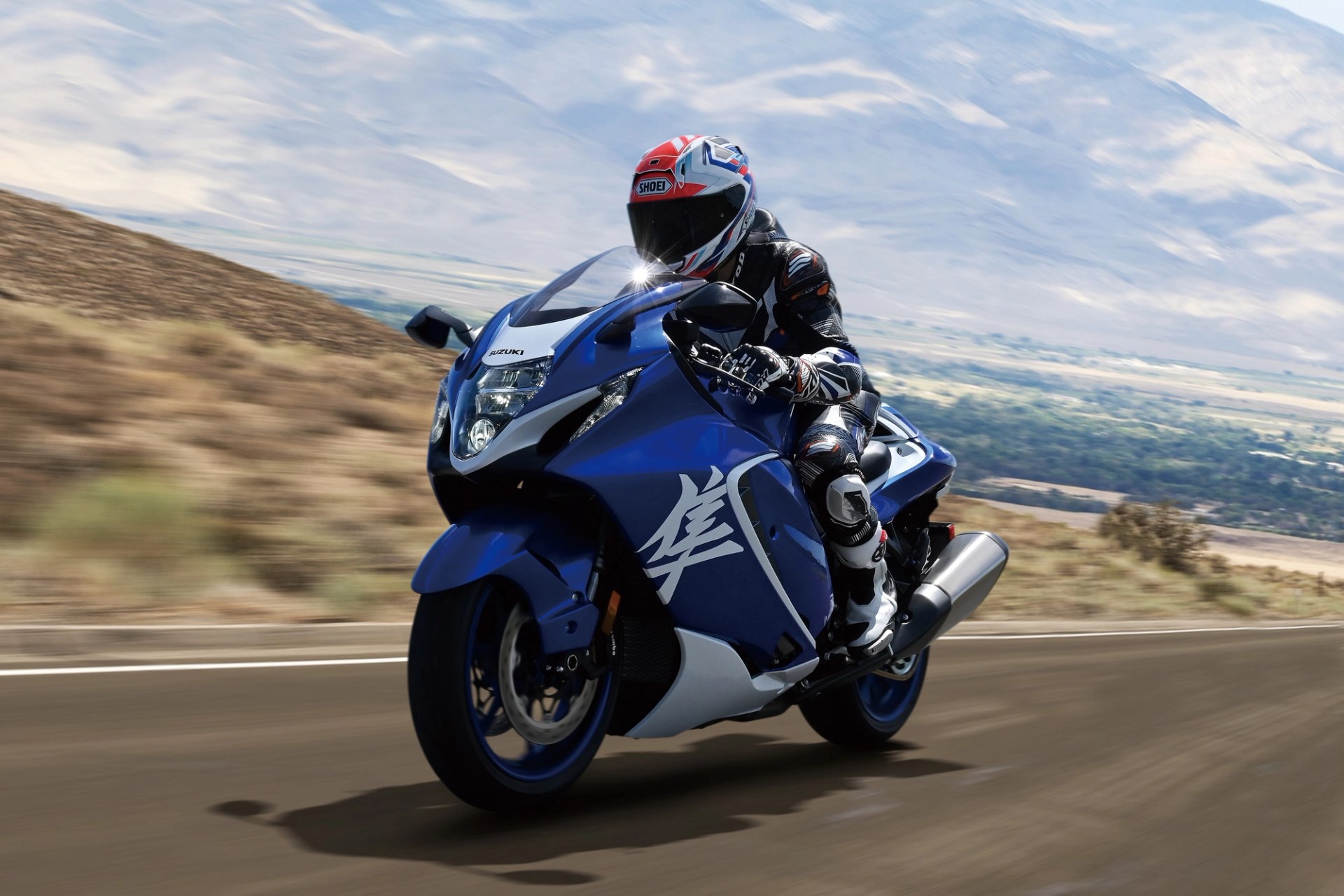 Piloto conduciendo una Suzuki Hayabusa azul a alta velocidad en carretera de montaña