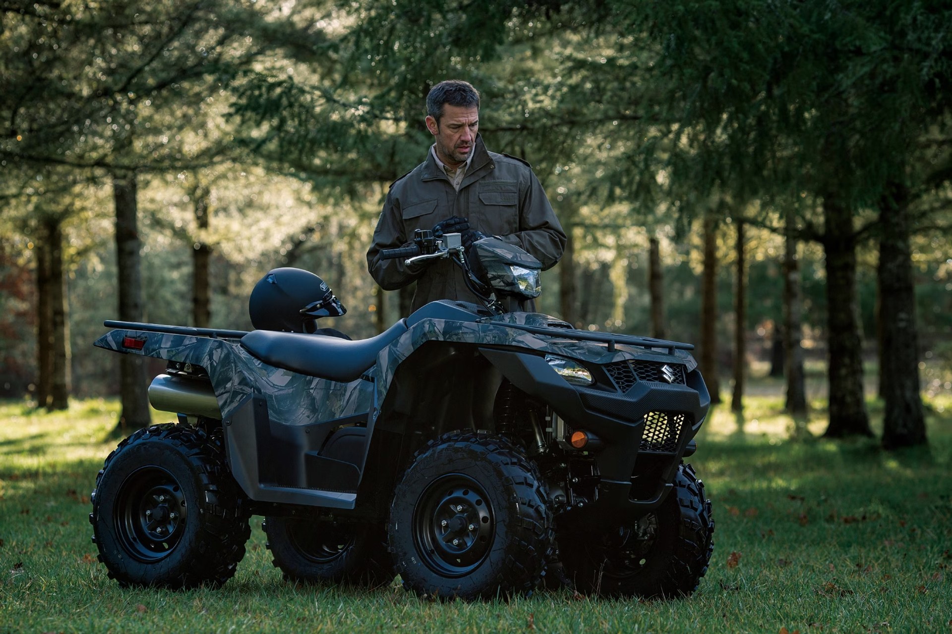 Suzuki KingQuad 750 camuflado junto a conductor en un entorno de bosque
