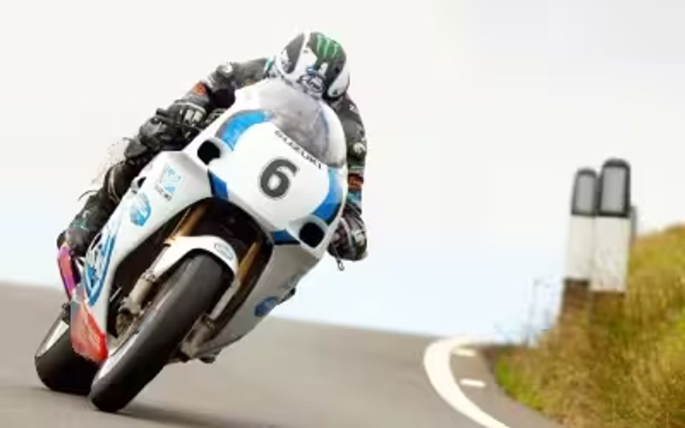 Piloto de competición conduciendo una motocicleta Suzuki de carreras número 6 en carretera