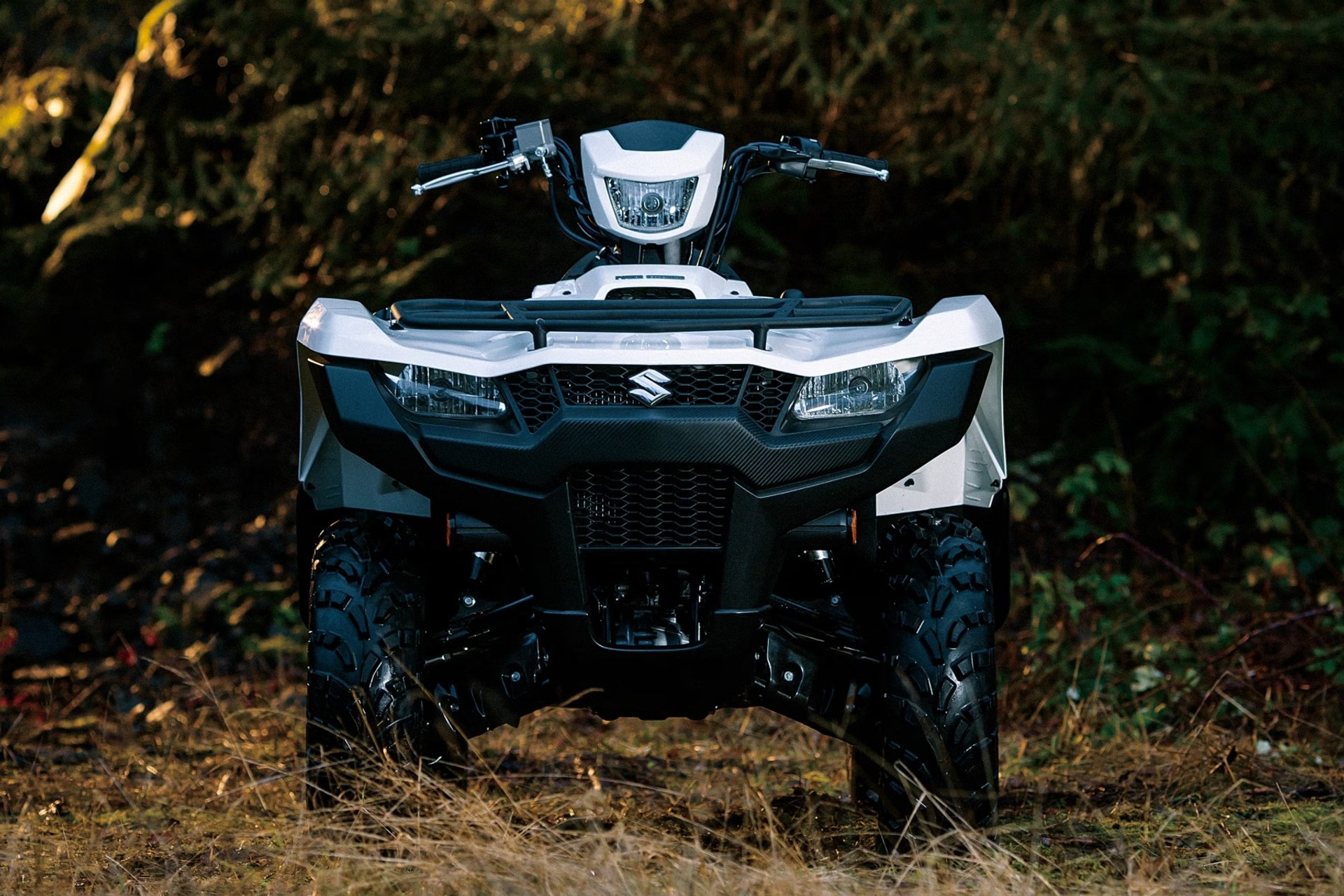 Suzuki KingQuad 750 blanco en vista frontal en un entorno de bosque