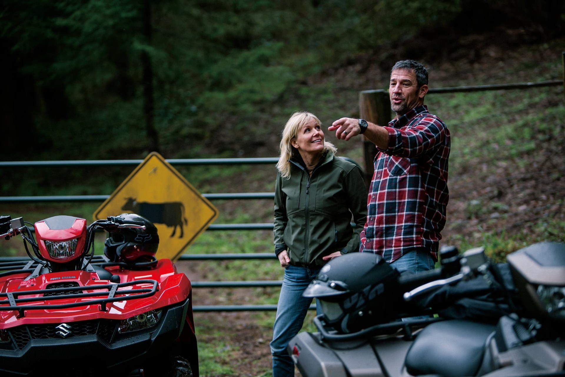 Dos personas junto a cuatrimotos Suzuki KingQuad 750 en un entorno rural y boscoso