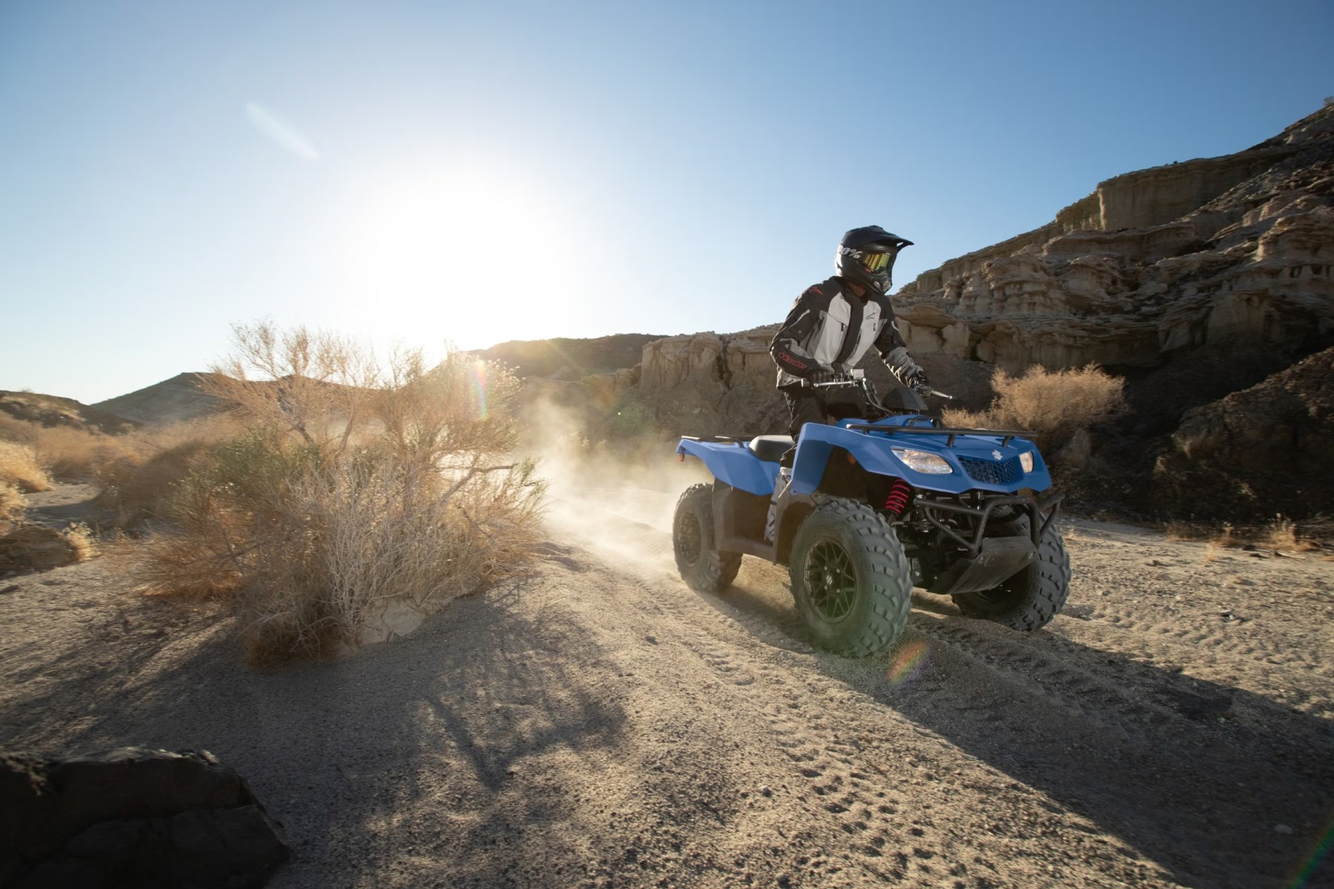 Conductor en Suzuki KingQuad 400 azul recorriendo un camino off-road en terreno desértico