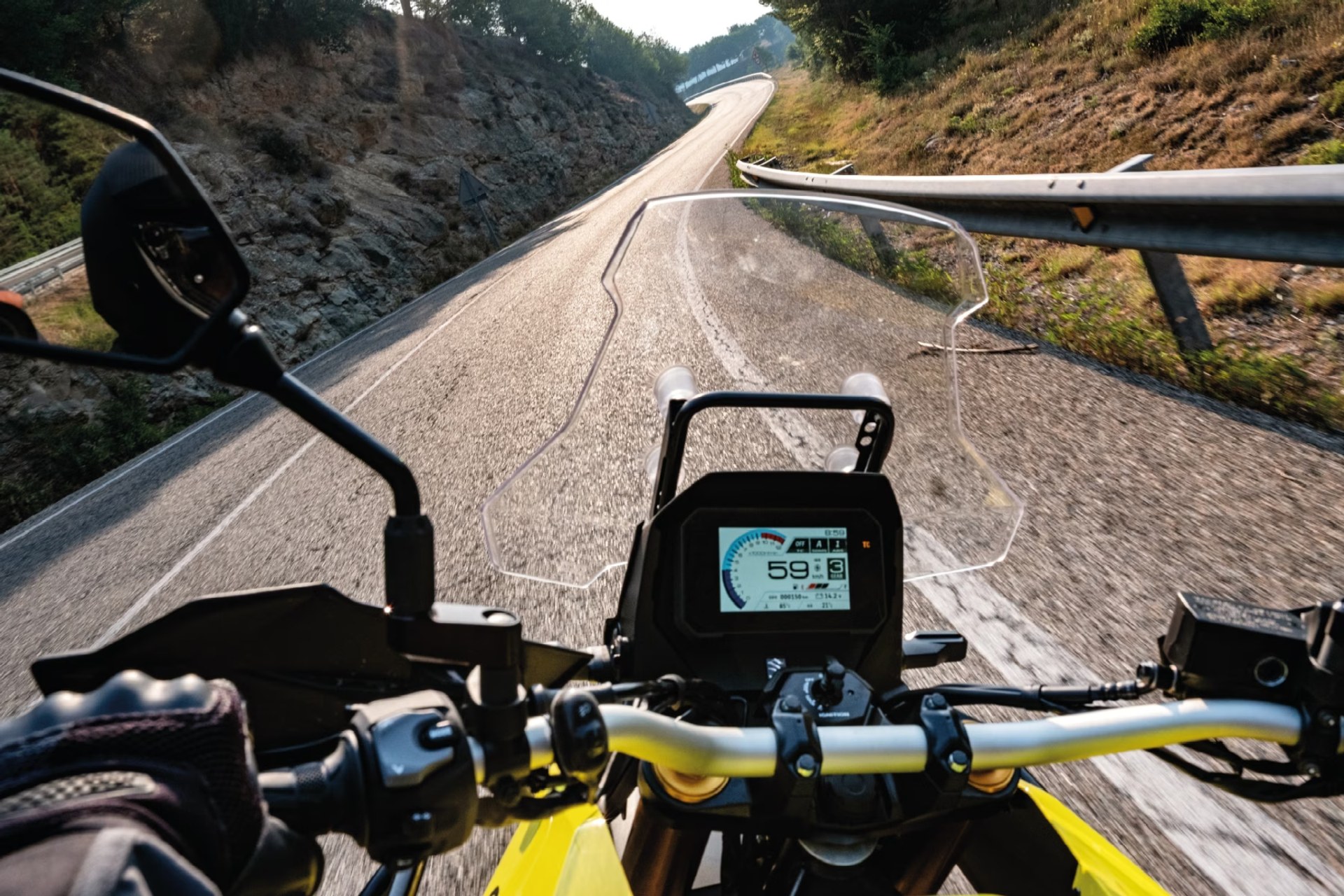 Vista en primera persona del manillar y la pantalla TFT de una Suzuki V-Strom 800DE en carretera
