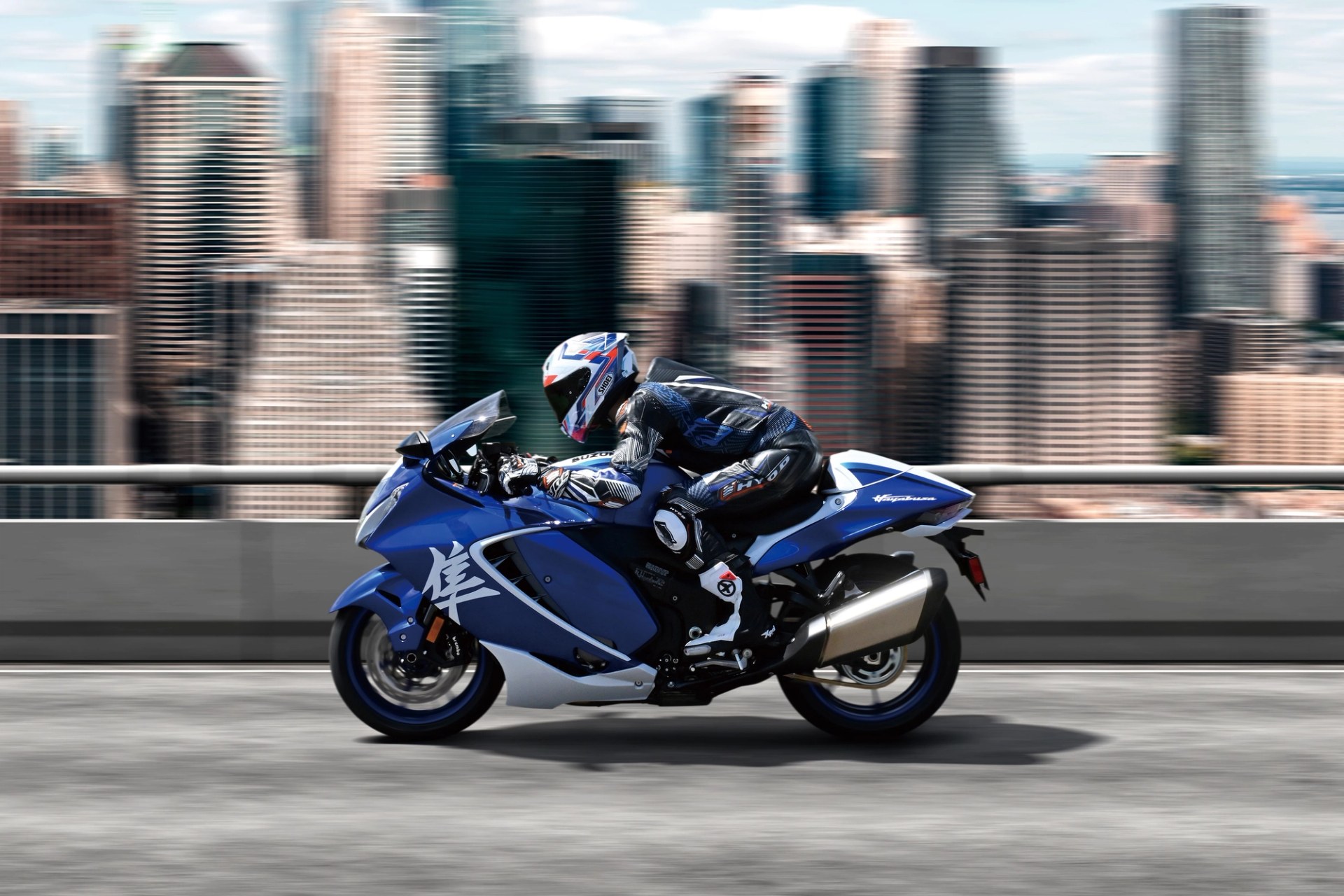 Piloto conduciendo una Suzuki Hayabusa azul a alta velocidad en entorno urbano