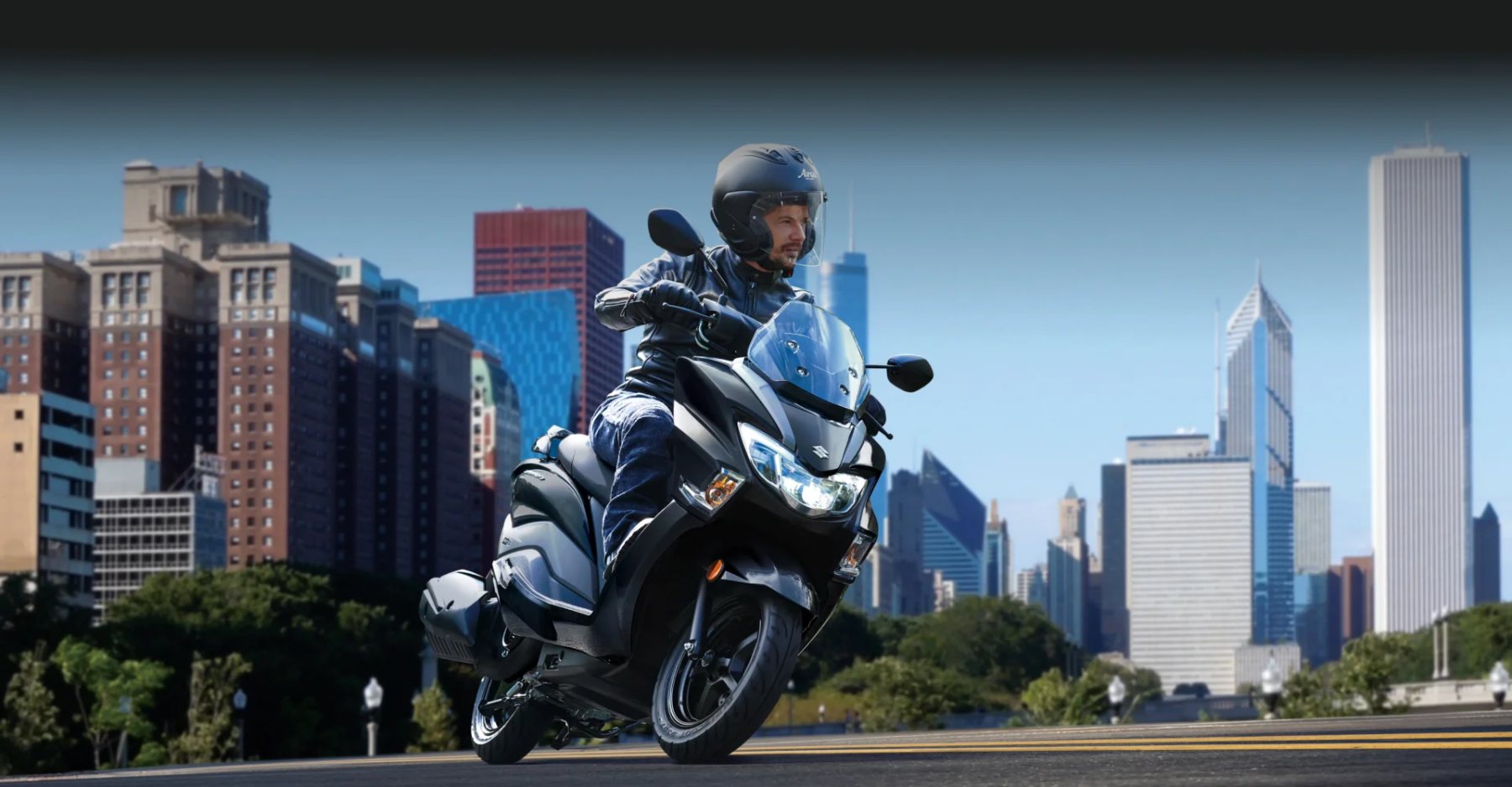 Tres scooters Suzuki Burgman Street 125 estacionadas con vista de ciudad al fondo