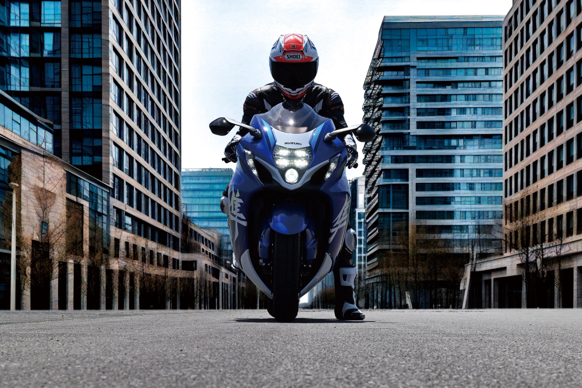Piloto sobre una Suzuki Hayabusa azul en una avenida urbana rodeada de edificios modernos