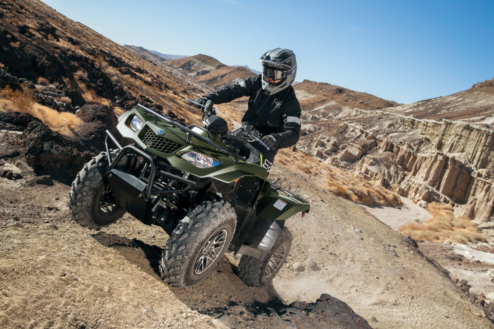 ALT recomendado: Conductor en Suzuki KingQuad 400 verde recorriendo terreno rocoso off-road