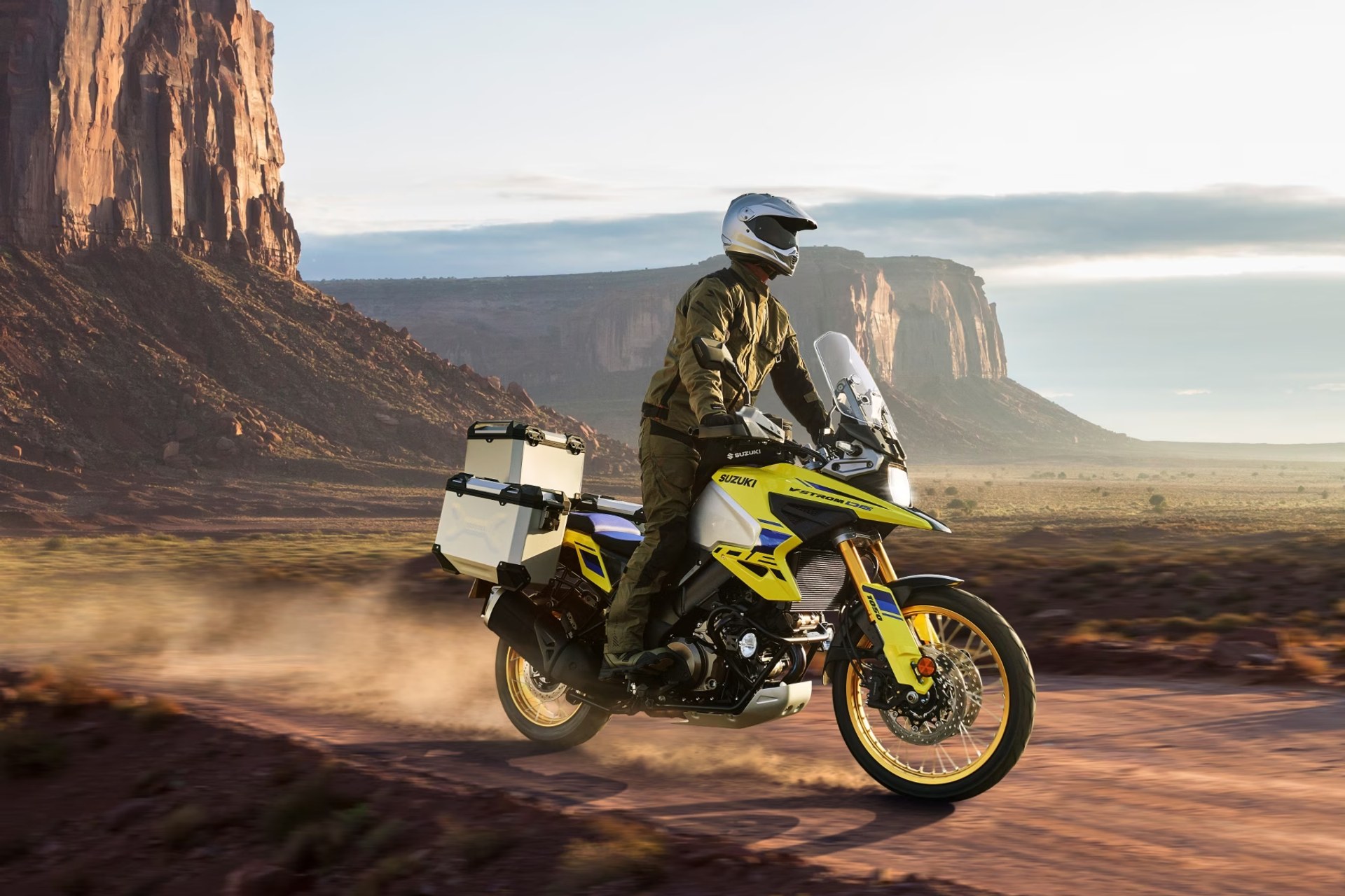 Motociclista en Suzuki V-Strom 1050DE amarilla recorriendo un camino off-road en paisaje desértico