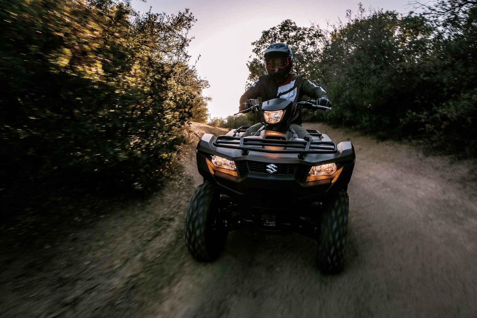 Conductor en Suzuki KingQuad 750 azul recorriendo un camino de tierra off-road