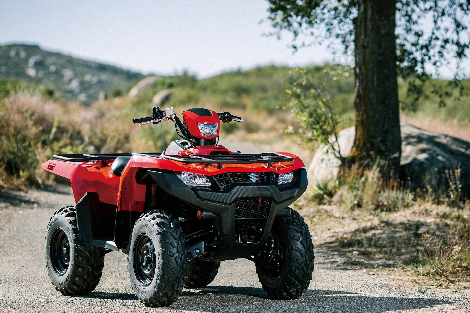 Suzuki KingQuad 750 rojo en vista frontal tres cuartos sobre camino de tierra