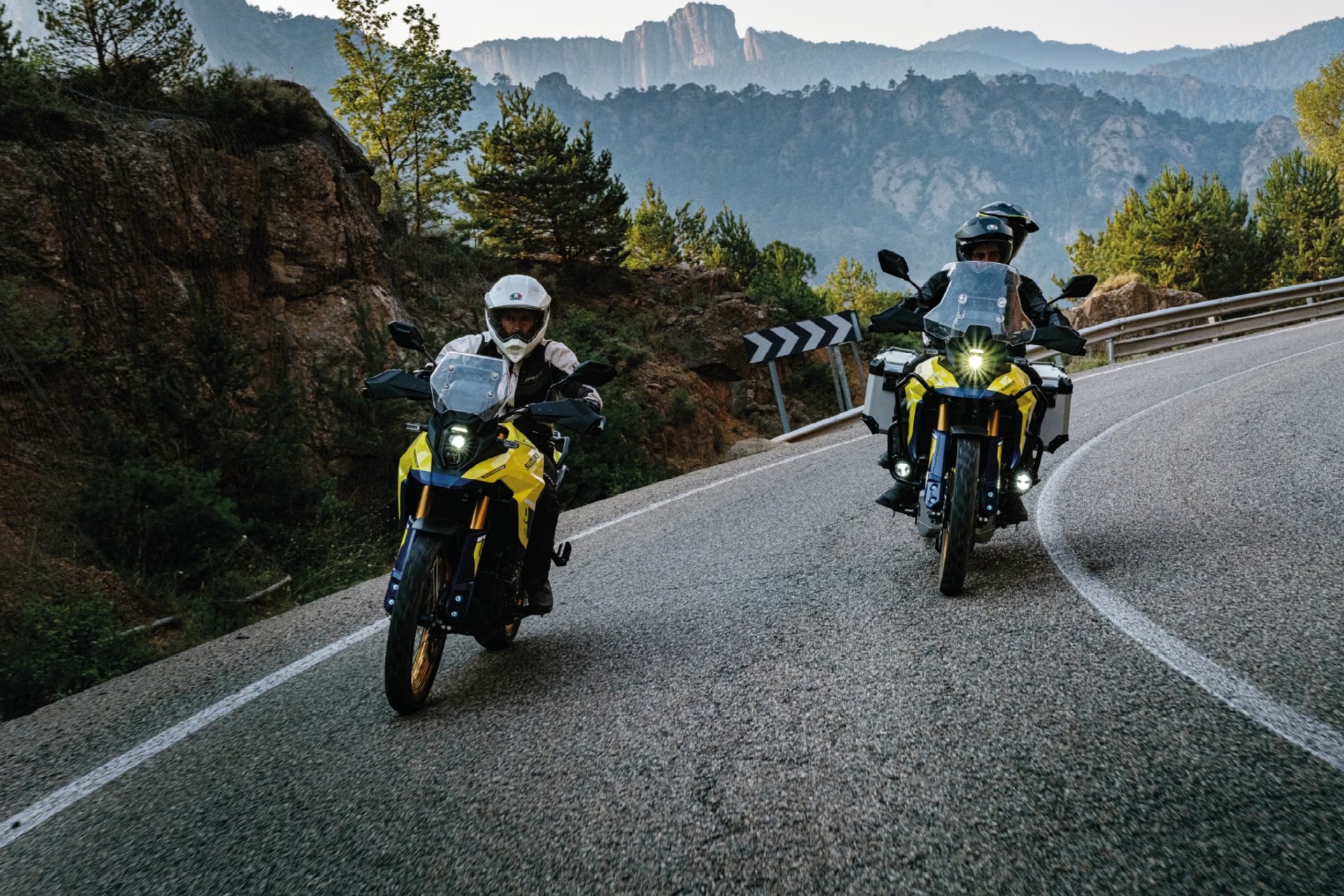Motociclistas en Suzuki V-Strom 800DE amarillas recorriendo una carretera de montaña