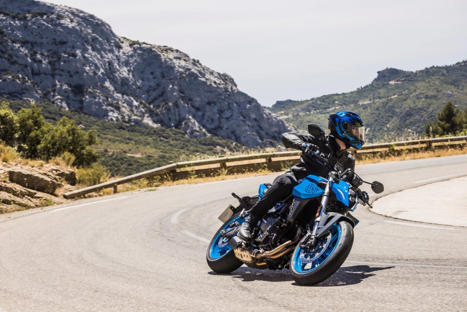 Piloto conduciendo una Suzuki GSX-8S azul en una carretera de montaña