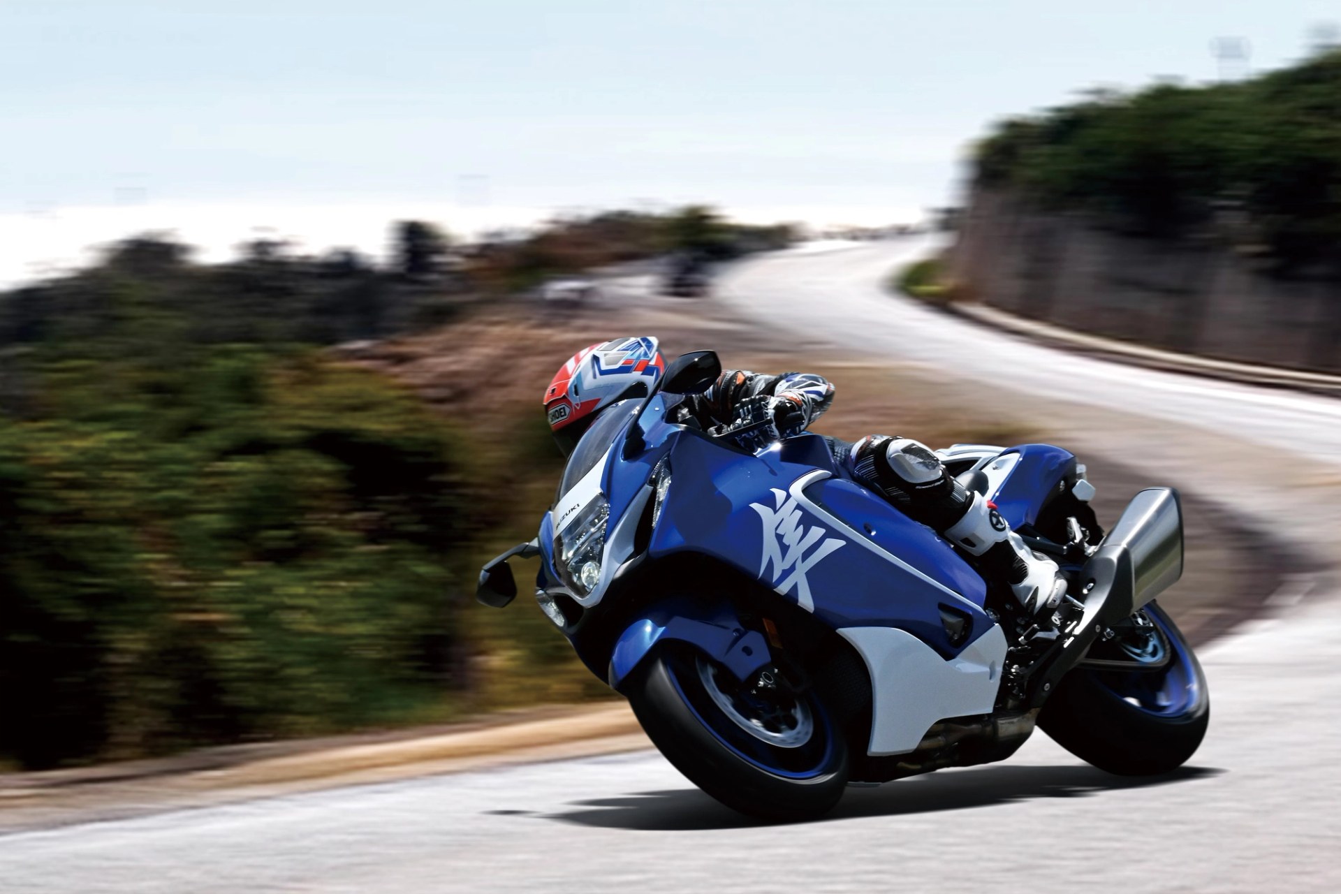 Piloto conduciendo una Suzuki Hayabusa azul en una curva de carretera