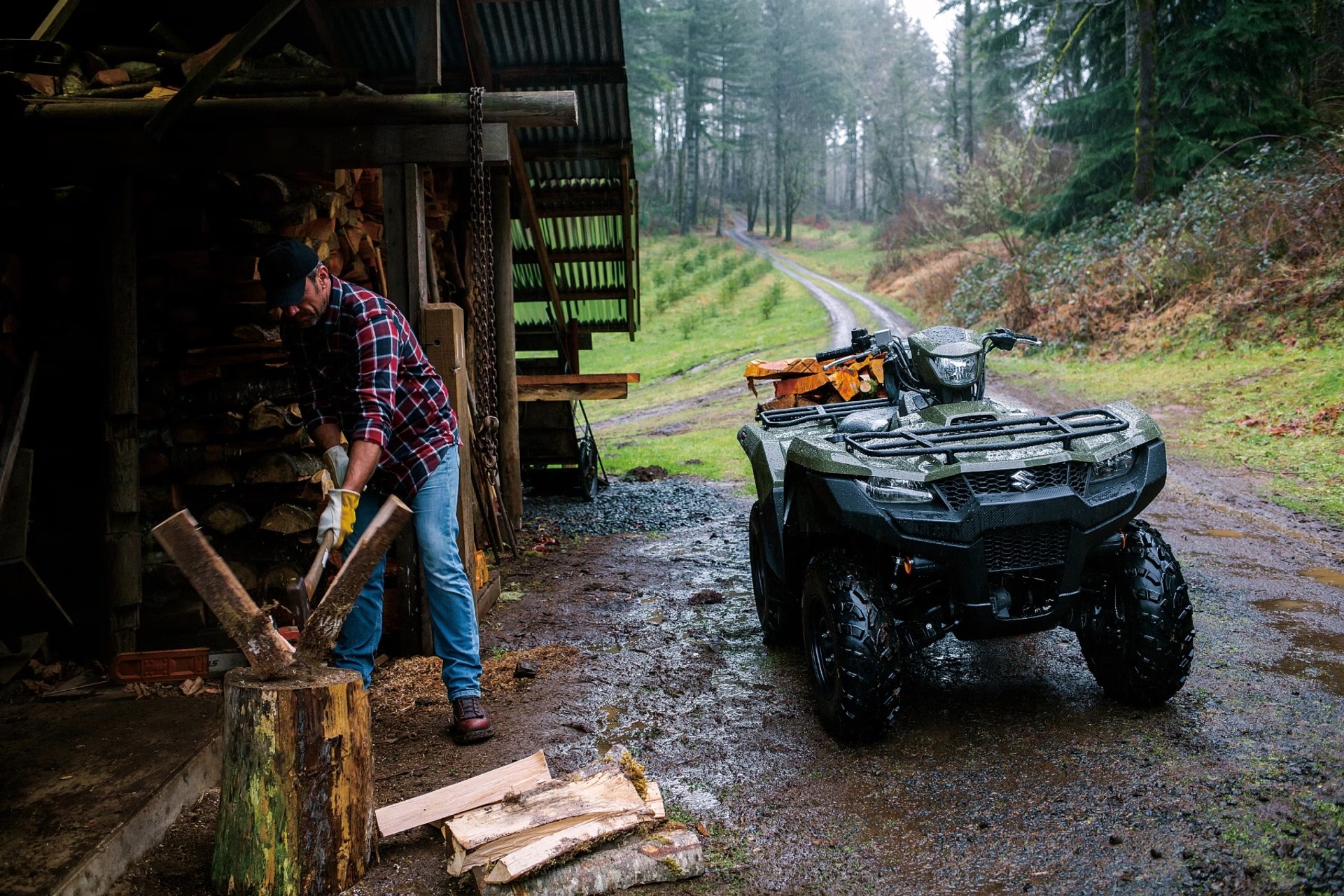 Suzuki KingQuad 750 junto a trabajador cortando leña en un entorno de bosque