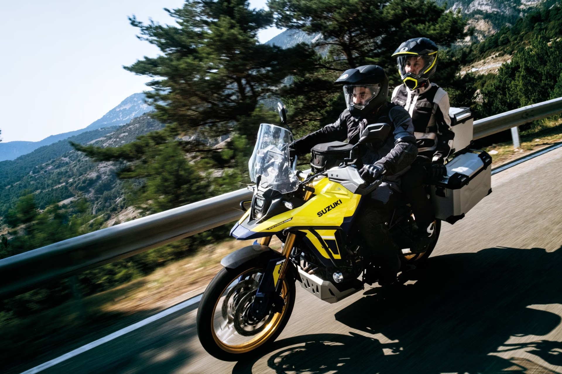 Suzuki V-Strom 800DE amarilla con dos motociclistas recorriendo una carretera de montaña