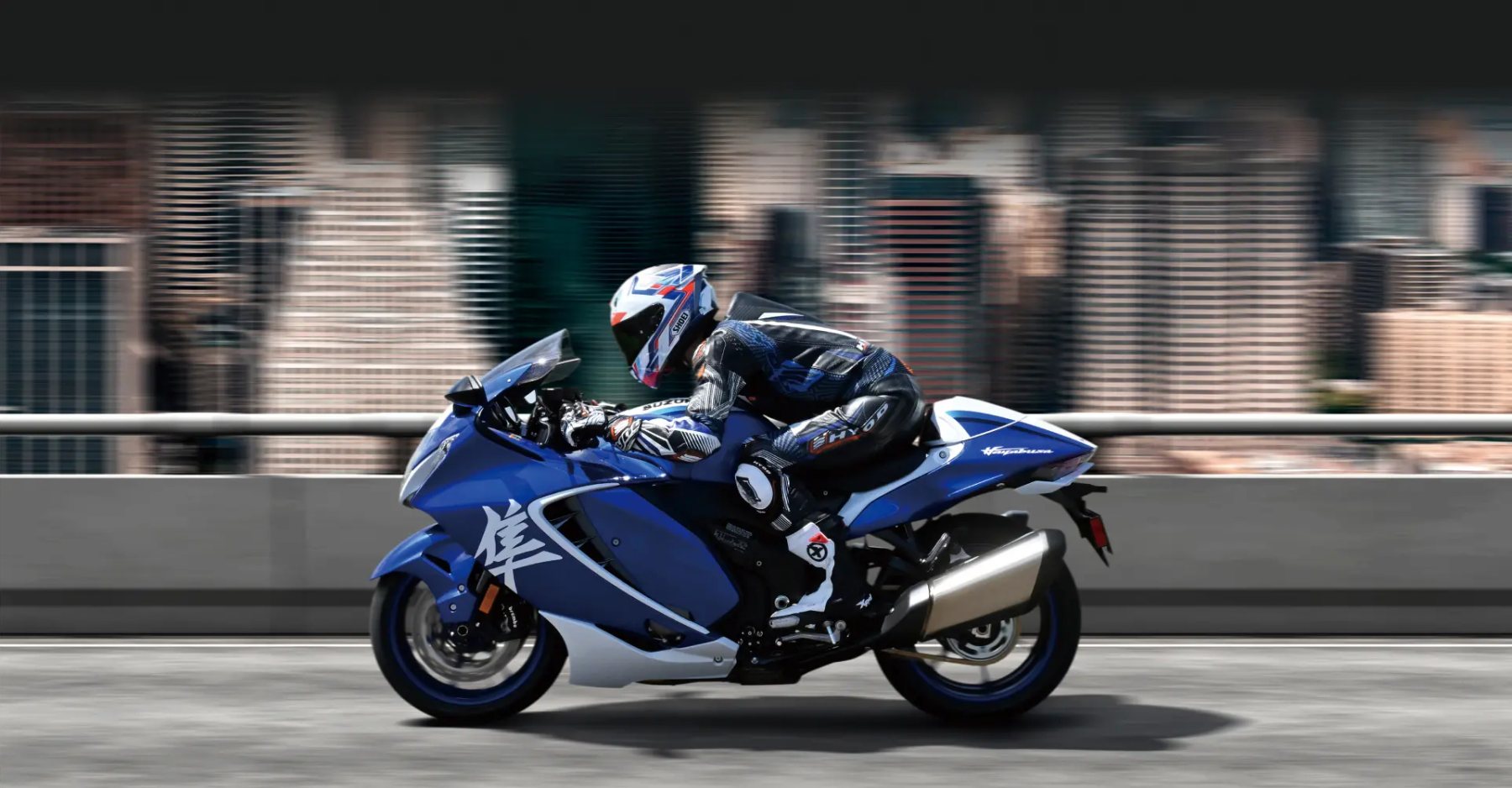 Piloto conduciendo una Suzuki Hayabusa azul a alta velocidad en entorno urbano