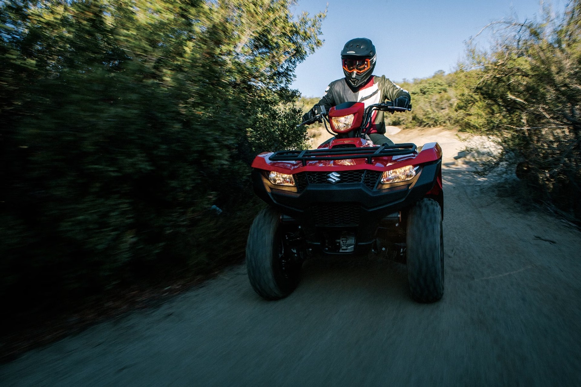 Conductor en Suzuki KingQuad 750 rojo recorriendo un camino off-road