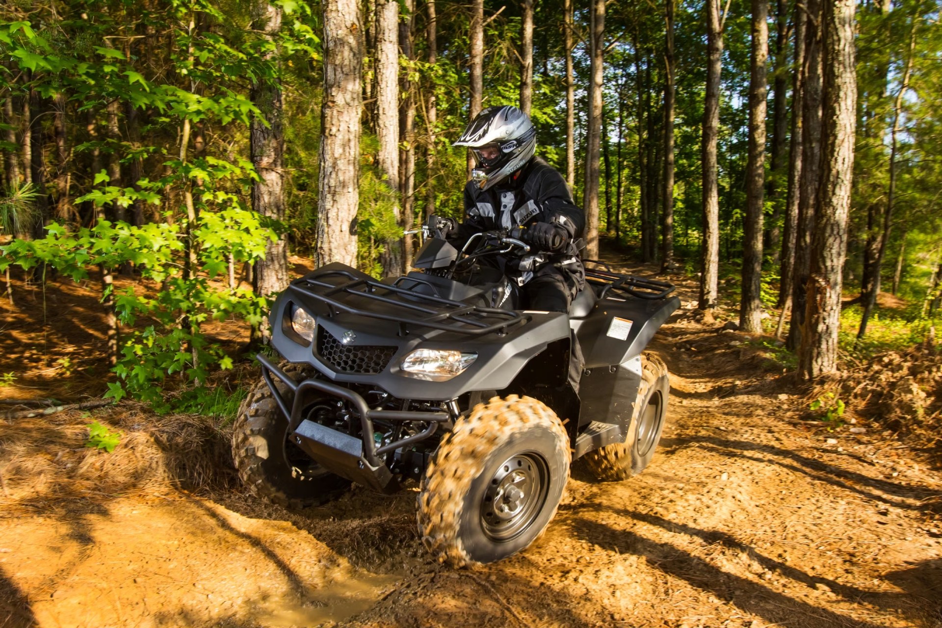 Conductor en Suzuki KingQuad 400 negro recorriendo un sendero de bosque